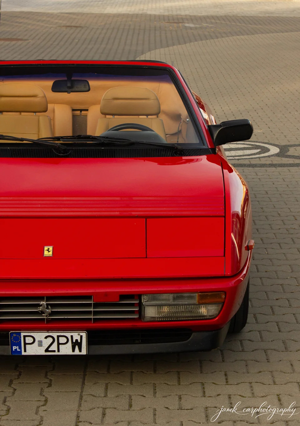 Czerwone Ferrari z otwartym dachem i beżowym wnętrzem, sfotografowane od przodu