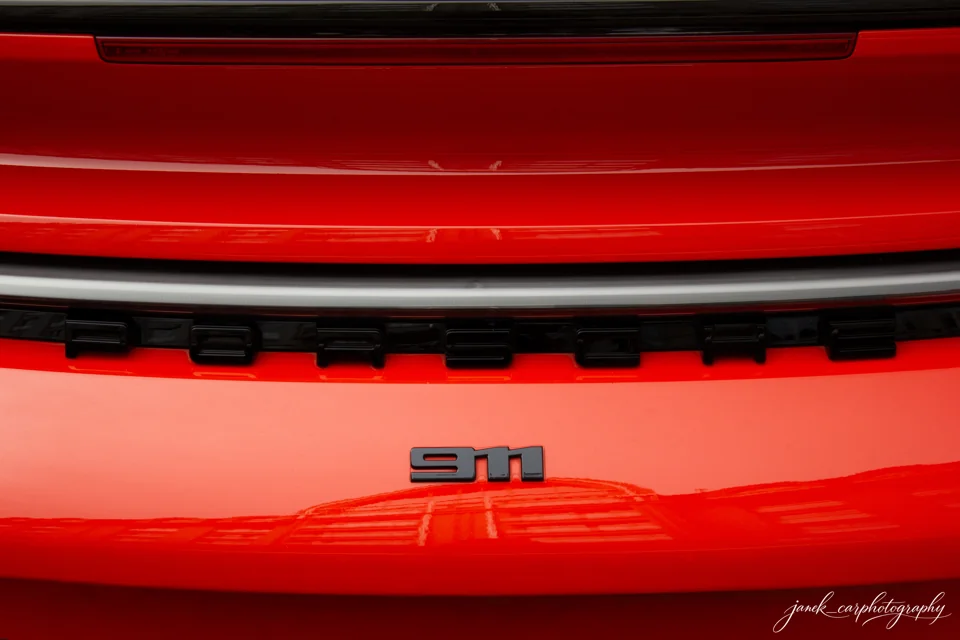 Emblemat Porsche i oznaczenie 911 na czerwonej tylnej części samochodu